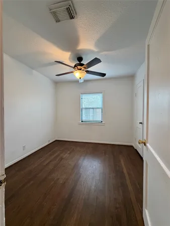 an empty room with wooden floor chandelier fan and windows