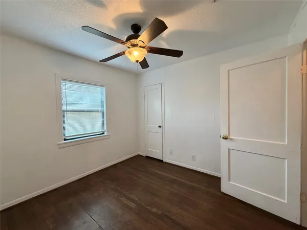 an empty room with wooden floor fan and windows