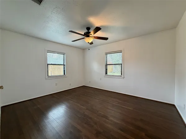 a view of a room with wooden floor and a ceiling fan