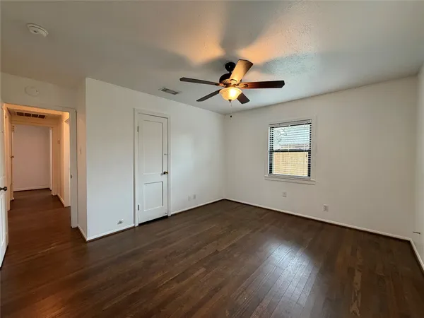 an empty room with wooden floor a ceiling fan and windows