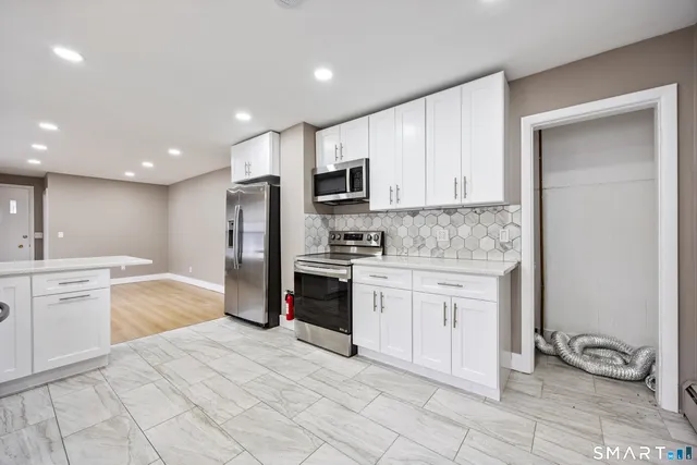 a kitchen with granite countertop a refrigerator stove top oven and sink