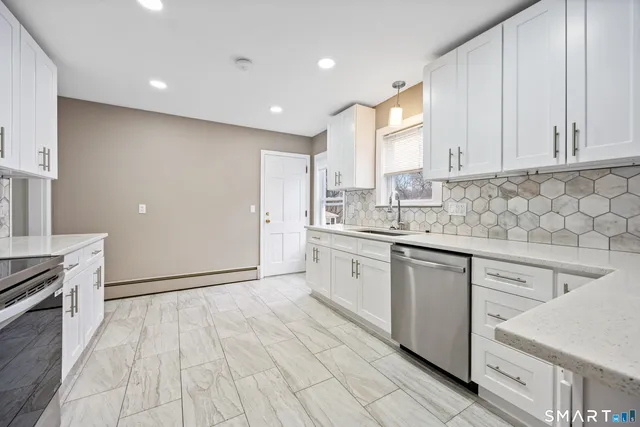 a kitchen with granite countertop a sink stainless steel appliances and white cabinets