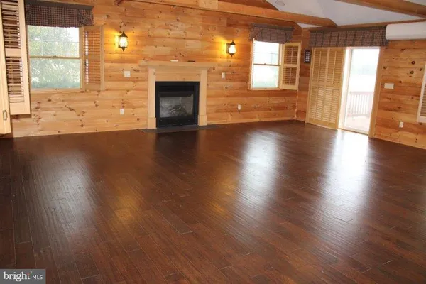 an empty room with wooden floor and a fireplace