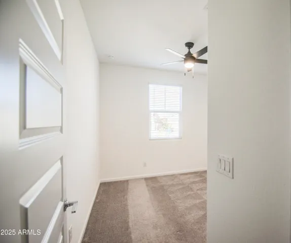 an empty room with a window and a ceiling fan