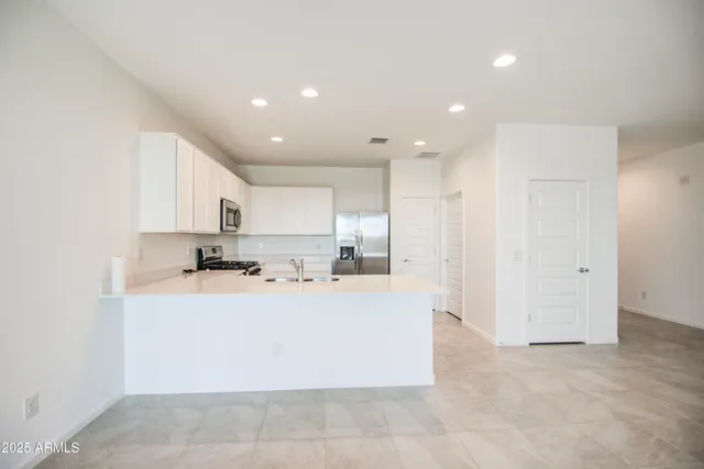 a large white kitchen with kitchen island a sink a stove and a refrigerator