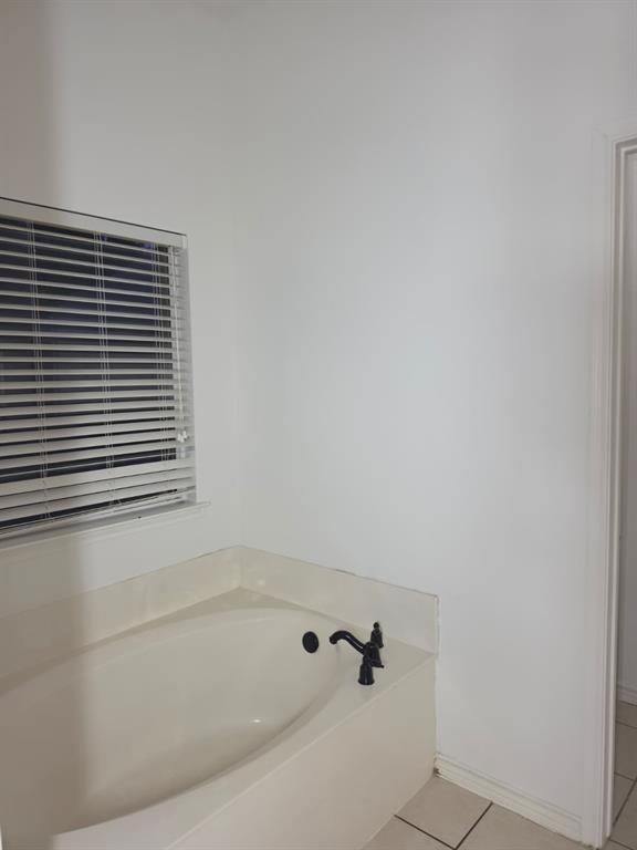 8047 New Kent Road Frisco, TX 75035 - Photo 25 of 27 Built-in soaking tub with a dark bronze faucet, framed by a window with horizontal blinds