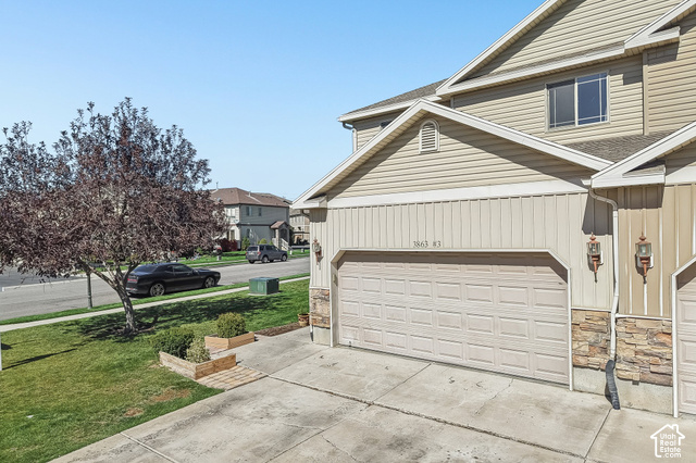 3863 East Cascade Road, Unit 3 Eagle Mountain, UT 84005 - Photo 2 of 37 Exterior with siding and stone accents, featuring a two-car garage, concrete driveway, and front lawn with a mature tree
