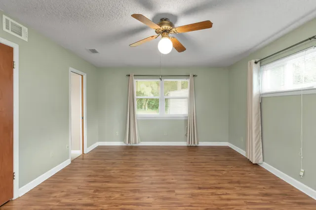 a view of empty room with wooden floor and fan