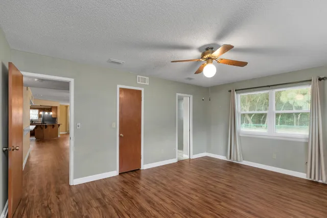 an empty room with wooden floor ceiling fan and windows