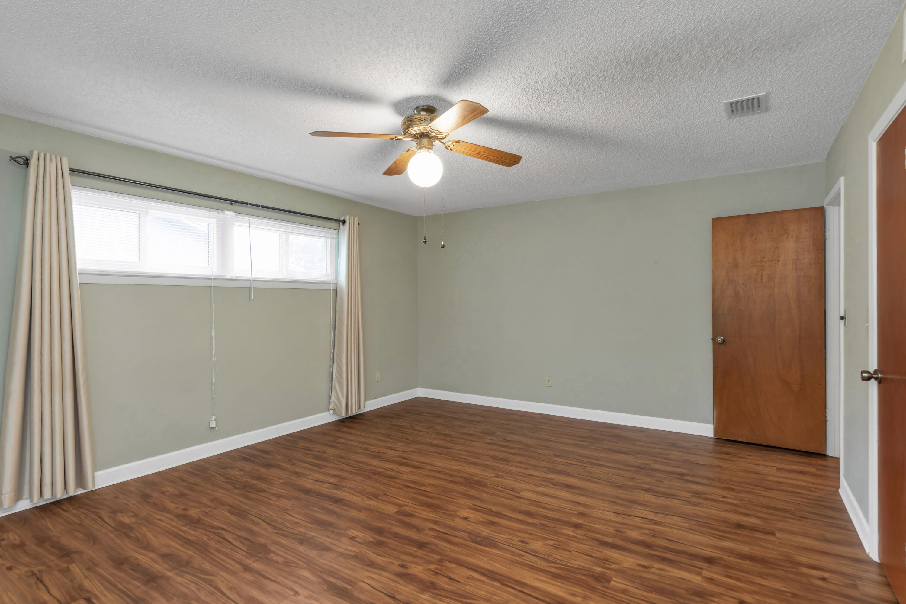 129 12th Avenue Shalimar, FL 32579 - Photo 25 of 36 an empty room with wooden floor chandelier fan and windows