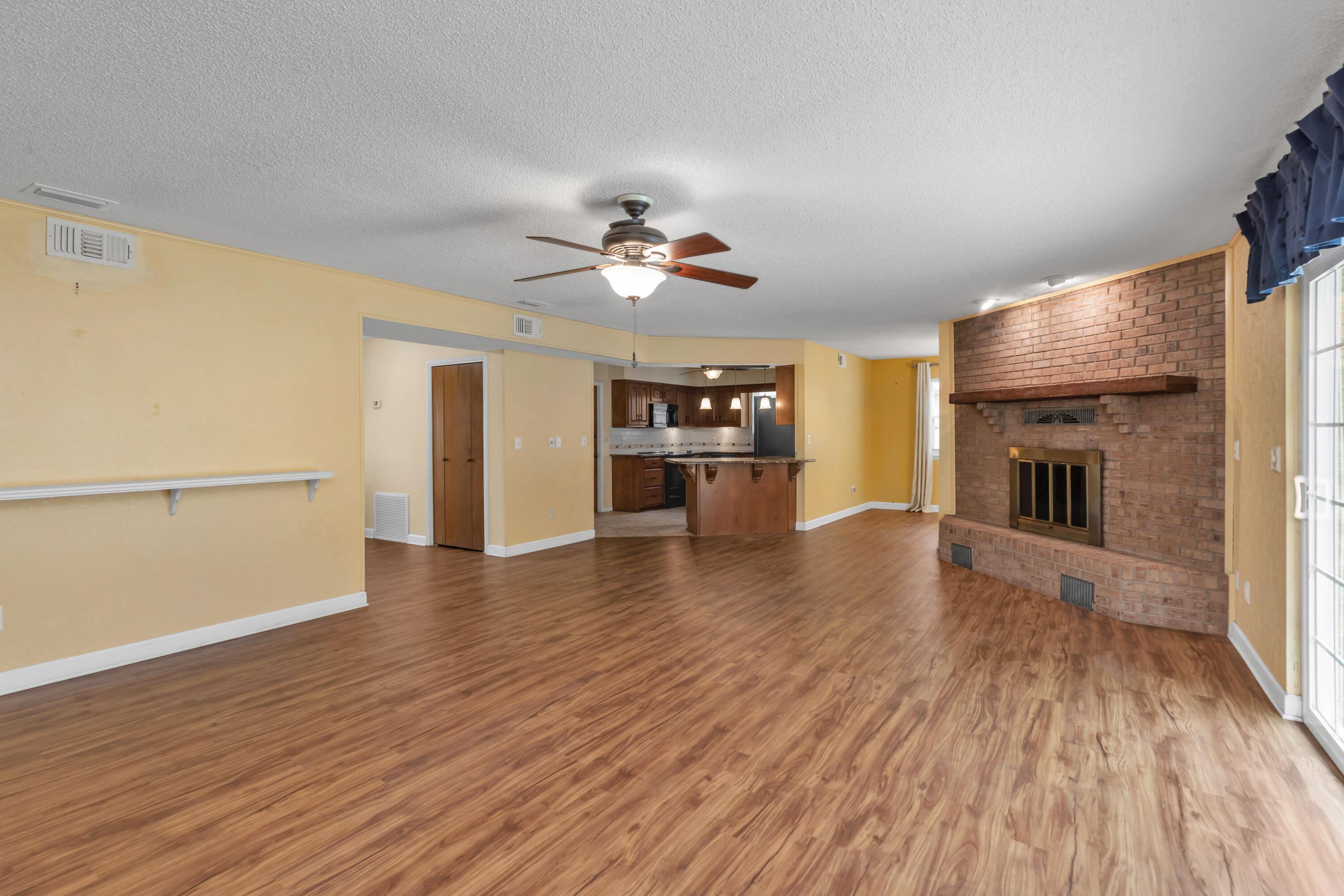 129 12th Avenue Shalimar, FL 32579 - Photo 5 of 36 an empty room with wooden floor fireplace and a kitchen space