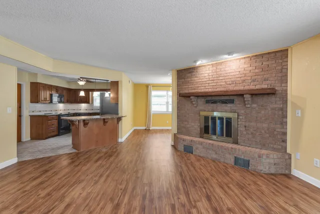 a open kitchen with kitchen island a sink dishwasher stove and oven with wooden floor