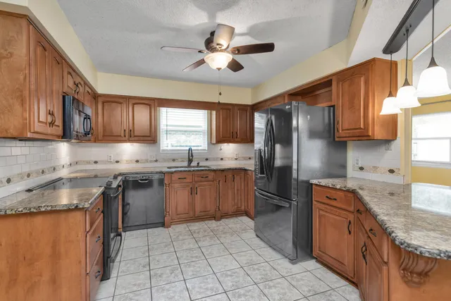 a kitchen with stainless steel appliances granite countertop a sink stove microwave and refrigerator