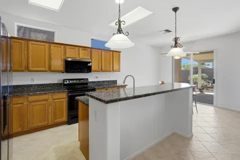 a kitchen with stainless steel appliances granite countertop a sink a stove and a wooden floors