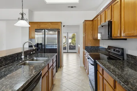 a kitchen with granite countertop a sink a counter top space and stainless steel appliances