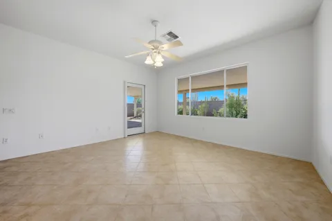 an empty room with chandelier fan and windows