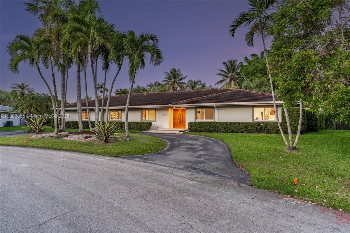 a view of a house with a yard and palm trees