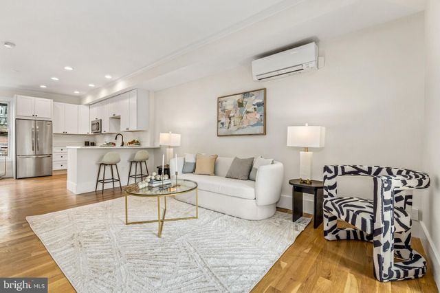 a living room with furniture and kitchen view with wooden floor