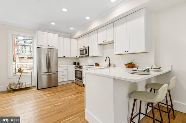 a kitchen with a refrigerator a stove a sink and a oven with wooden floor