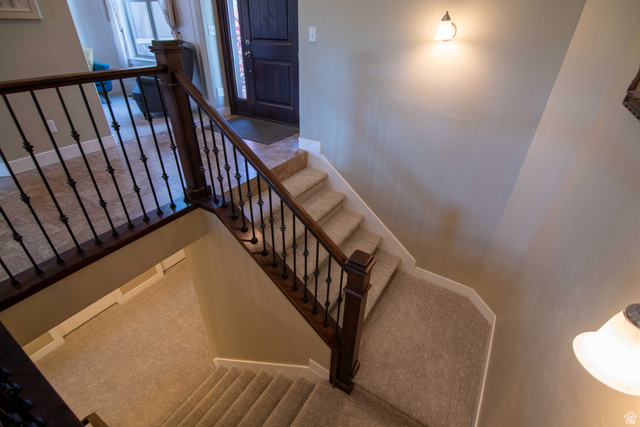 646 East 1400th Street North Mapleton, UT 84664 - Photo 35 of 78 Staircase featuring dark wood handrails, decorative wrought iron balusters, and light-toned carpeted treads