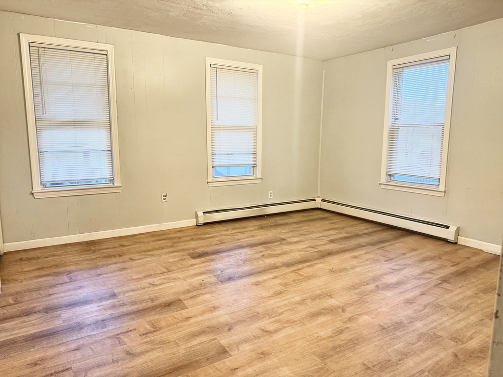 45 Mitchell Street, Unit 1 New Bedford, MA 02746 - Photo 2 of 11 an empty room with wooden floor and windows
