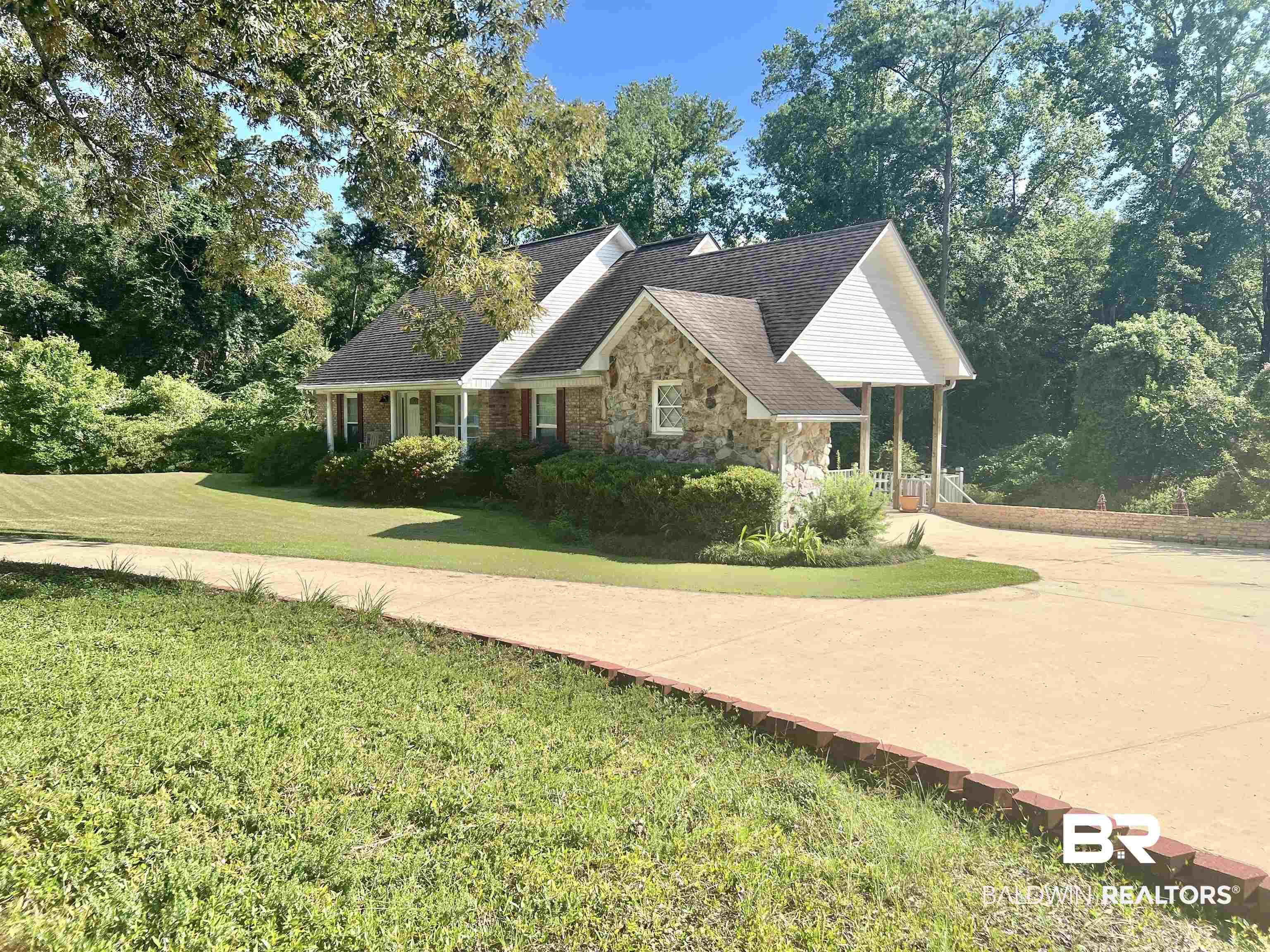 2691 Appleton Road Brewton, AL 36426 - Photo 3 of 60 View of front of home featuring stone siding, a front yard, a shingled roof, and covered porch
