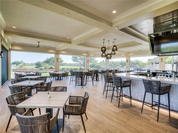 a room with lots of tables a large window and chairs