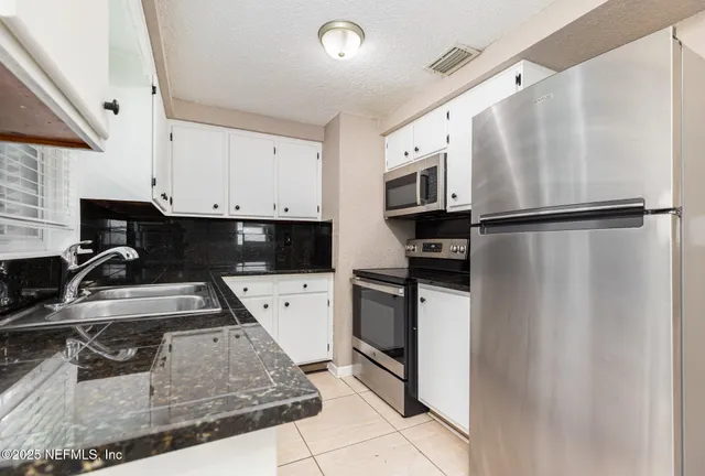 a kitchen with a refrigerator sink and white cabinets