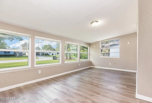 a view of an empty room with a window and a kitchen view