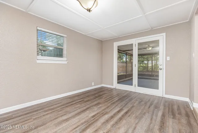 a view of an empty room with wooden floor and a window
