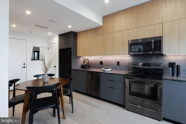 a kitchen with stainless steel appliances a stove a sink cabinets and a dining table