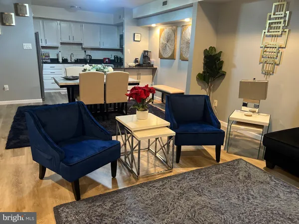 a living room with furniture and a dining table with kitchen appliances