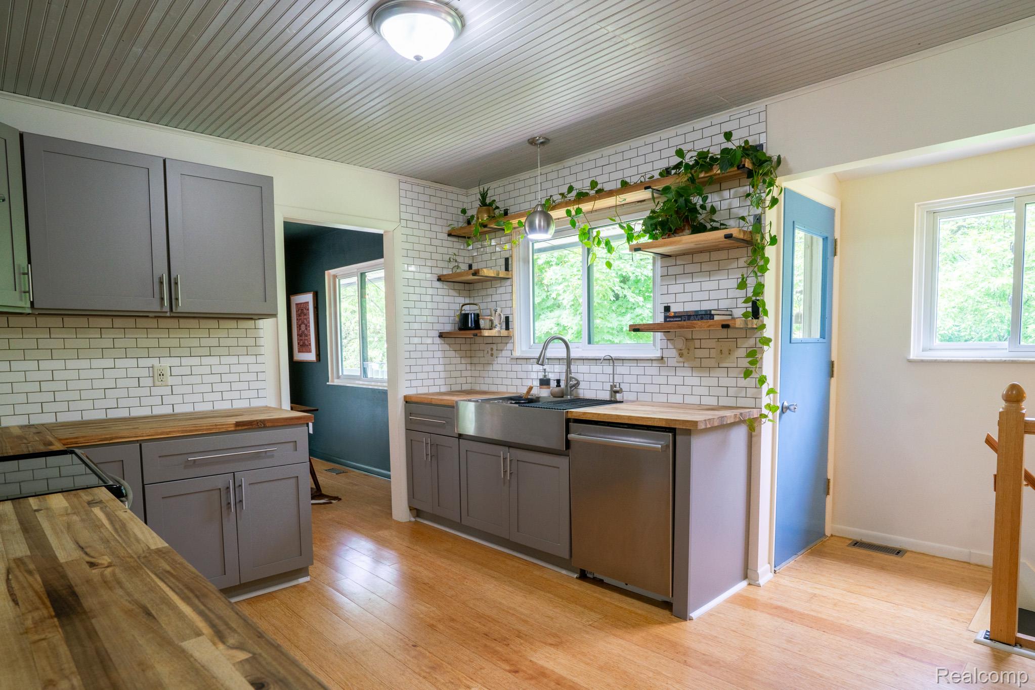 7333 Toma Road Dexter, MI 48130 - Photo 23 of 45 Kitchen featuring wood-finish flooring, subway tile backsplash, butcher block countertops, and stainless steel appliances