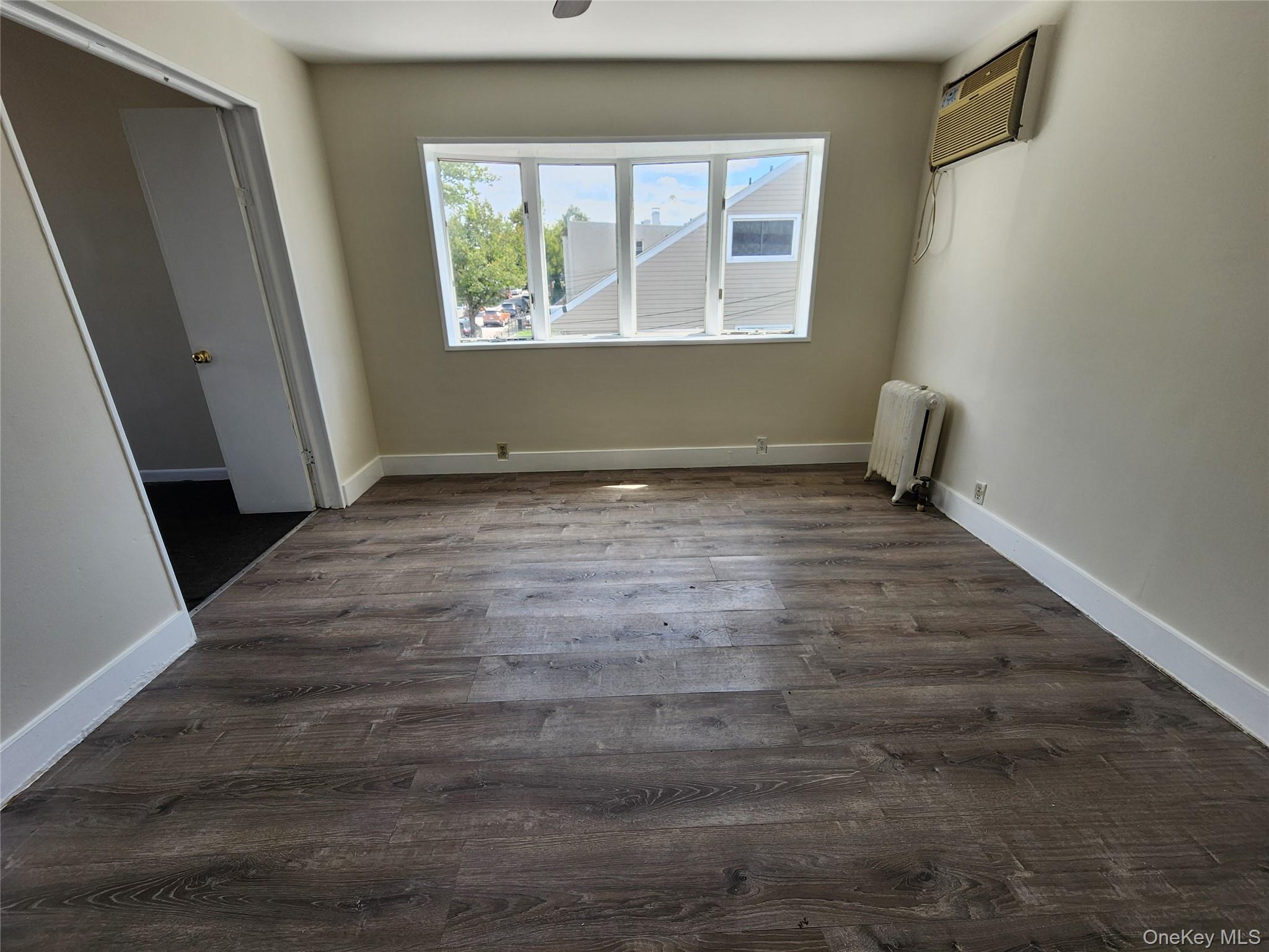 59-12 58th Road Queens, NY 11378 - Photo 8 of 21 an empty room with wooden floor and windows