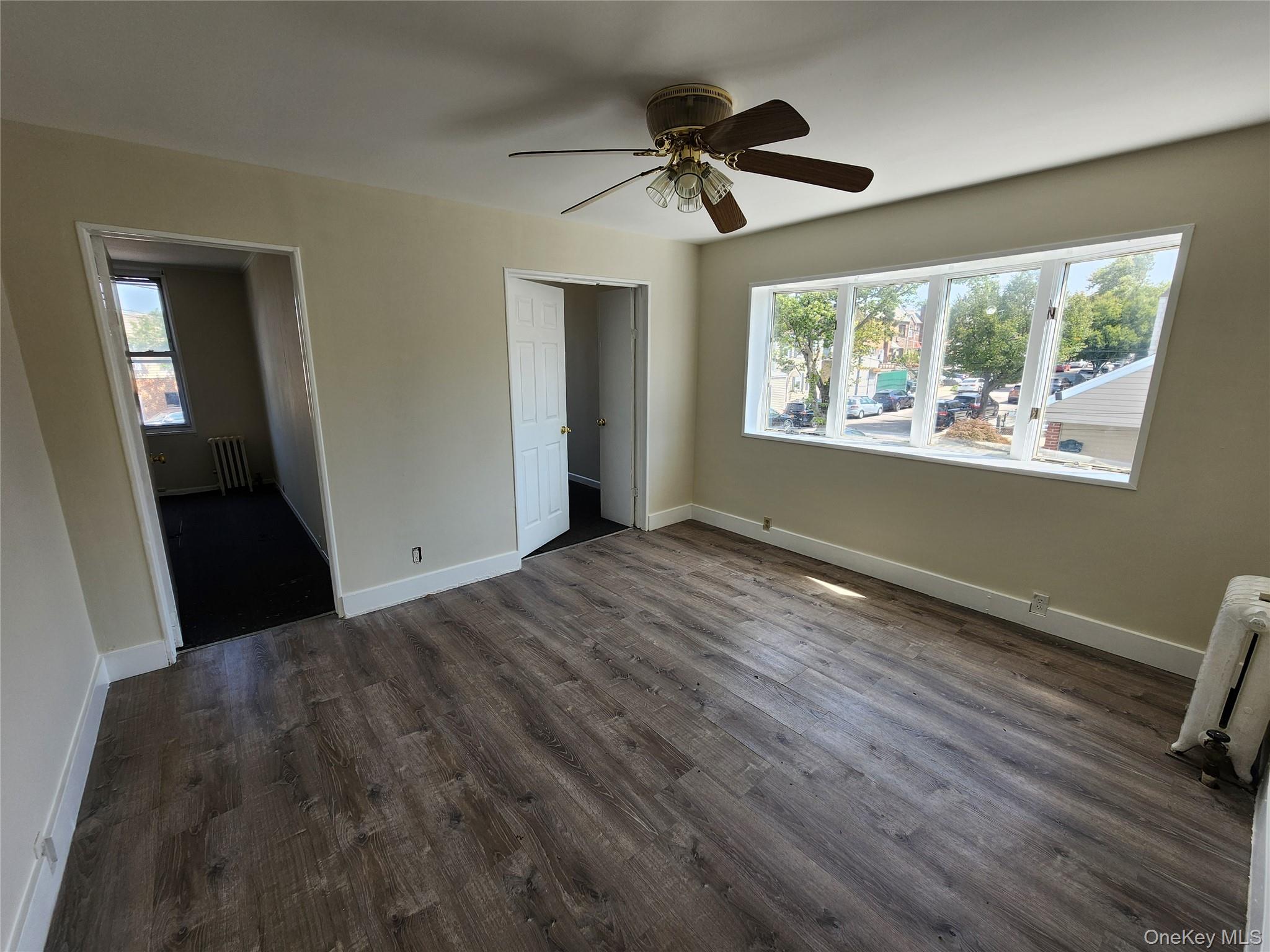 59-12 58th Road Queens, NY 11378 - Photo 9 of 21 a view of empty room with wooden floor and fan