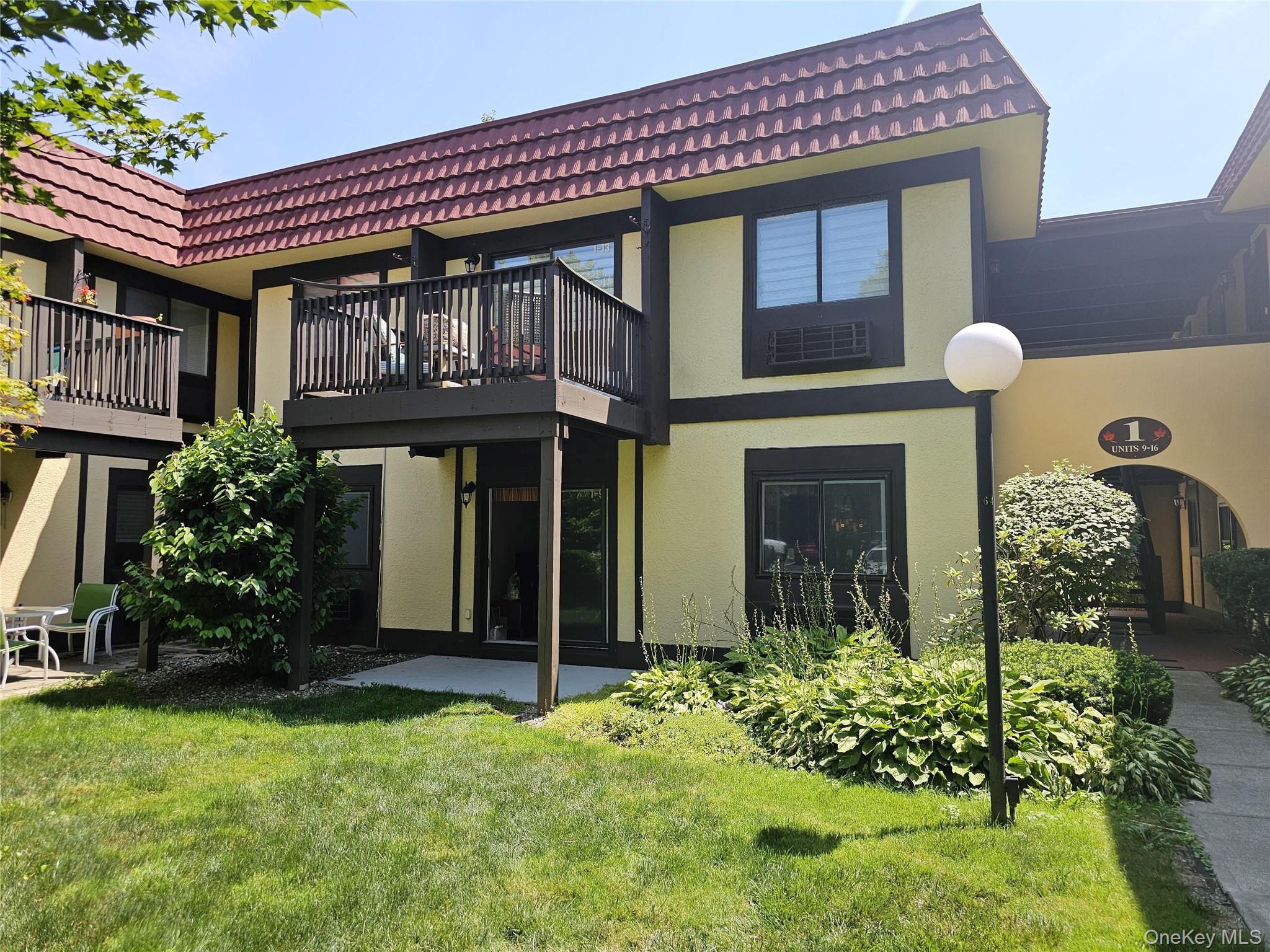front of condo and a patio area, a yard, and a tile roof