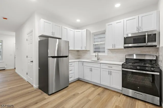a kitchen with cabinets stainless steel appliances and wooden floor
