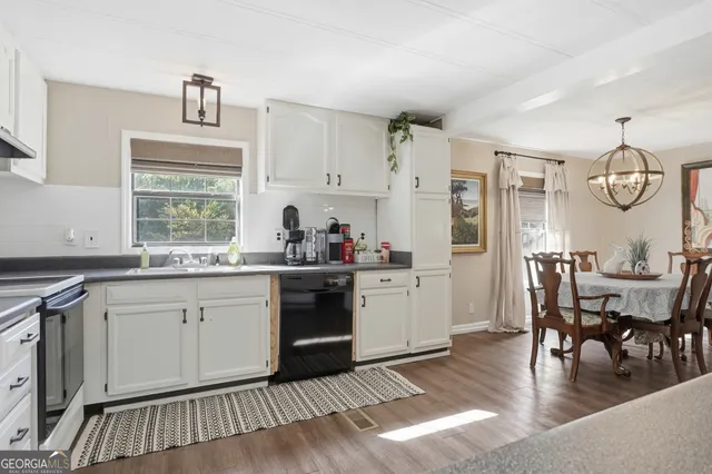 a kitchen with granite countertop a stove a sink dishwasher a dining table and chairs with wooden floor