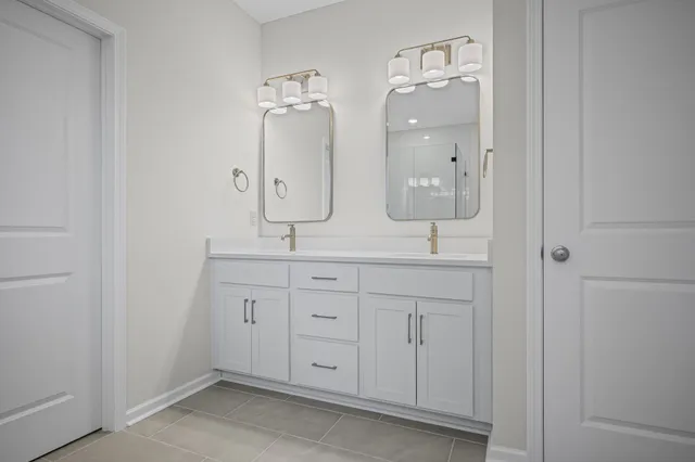 a bathroom with double vanity sink two mirror and window