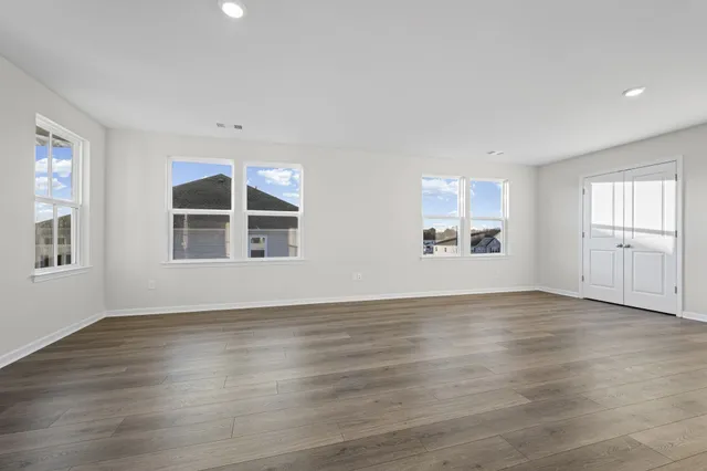 an empty room with wooden floor and windows