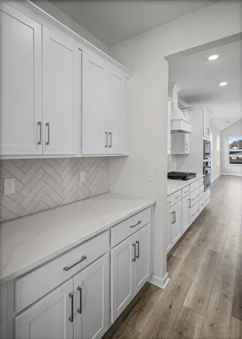 a view of a kitchen with stainless steel appliances granite countertop a stove a sink and white cabinets