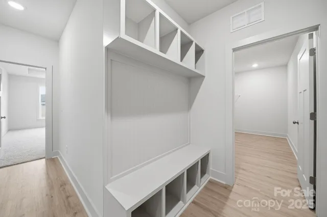 a view of an empty room with wooden floor and a bathroom