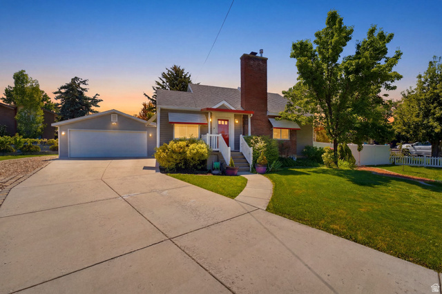 1925 South Main Street Bountiful, UT 84010 - Photo 1 of 48 Front exterior featuring a brick chimney, white picket fence, attached two-car garage, concrete driveway, and established landscaping