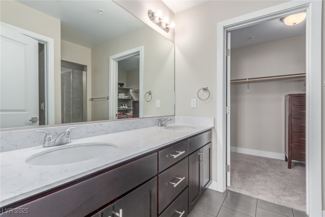3165 Via Como Henderson, NV 89044 - Photo 20 of 42 Bathroom featuring tile patterned floors, a walk in closet, double vanity, baseboards, and a shower with shower door