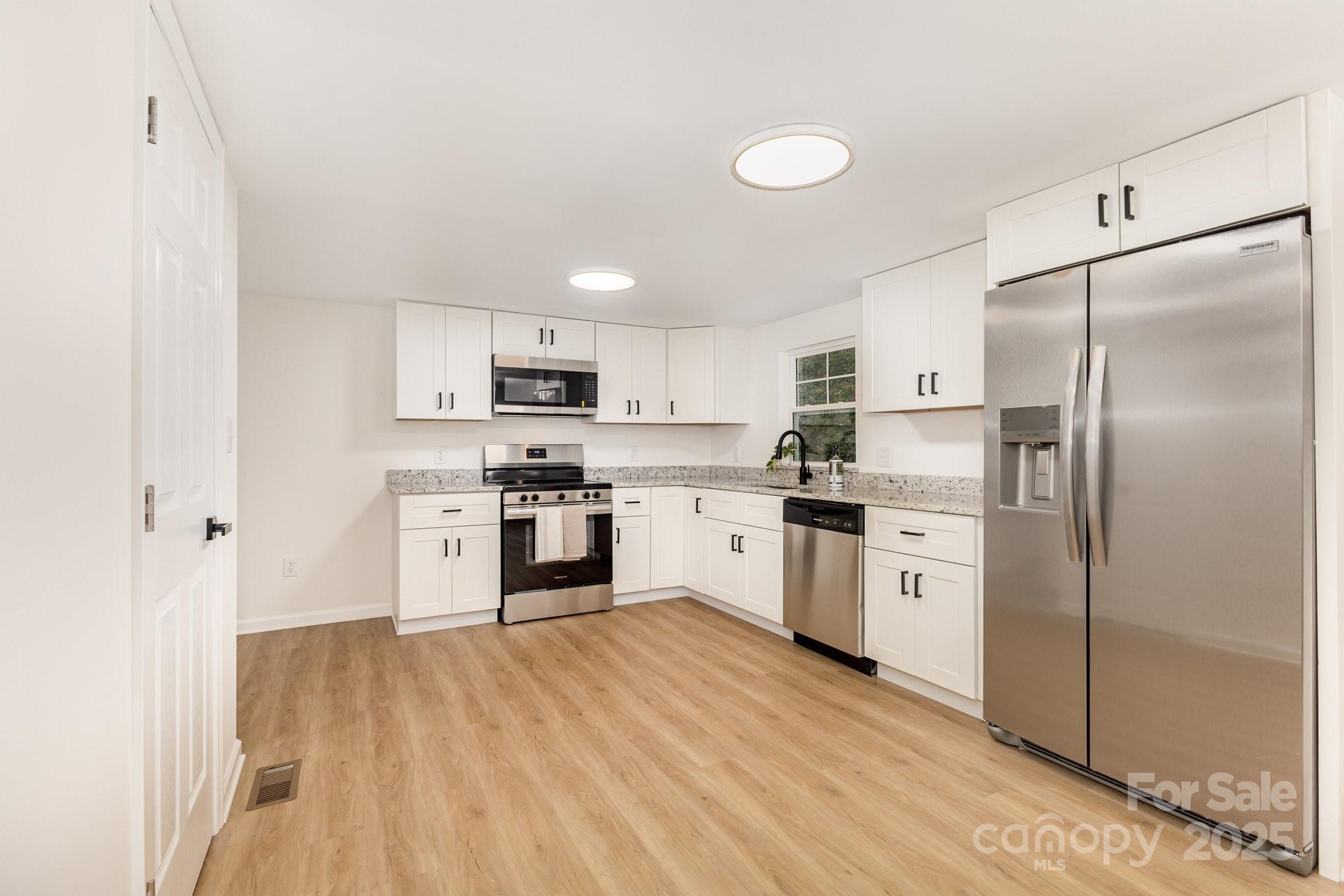 12180 A Coyle Road Stanfield, NC 28163 - Photo 6 of 16 a kitchen with white cabinets and stainless steel appliances