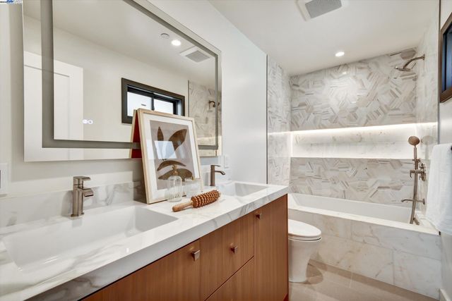a bathroom with a granite countertop sink mirror toilet and bathtub
