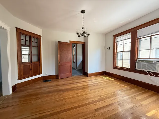a view of an empty room with window and wooden floor