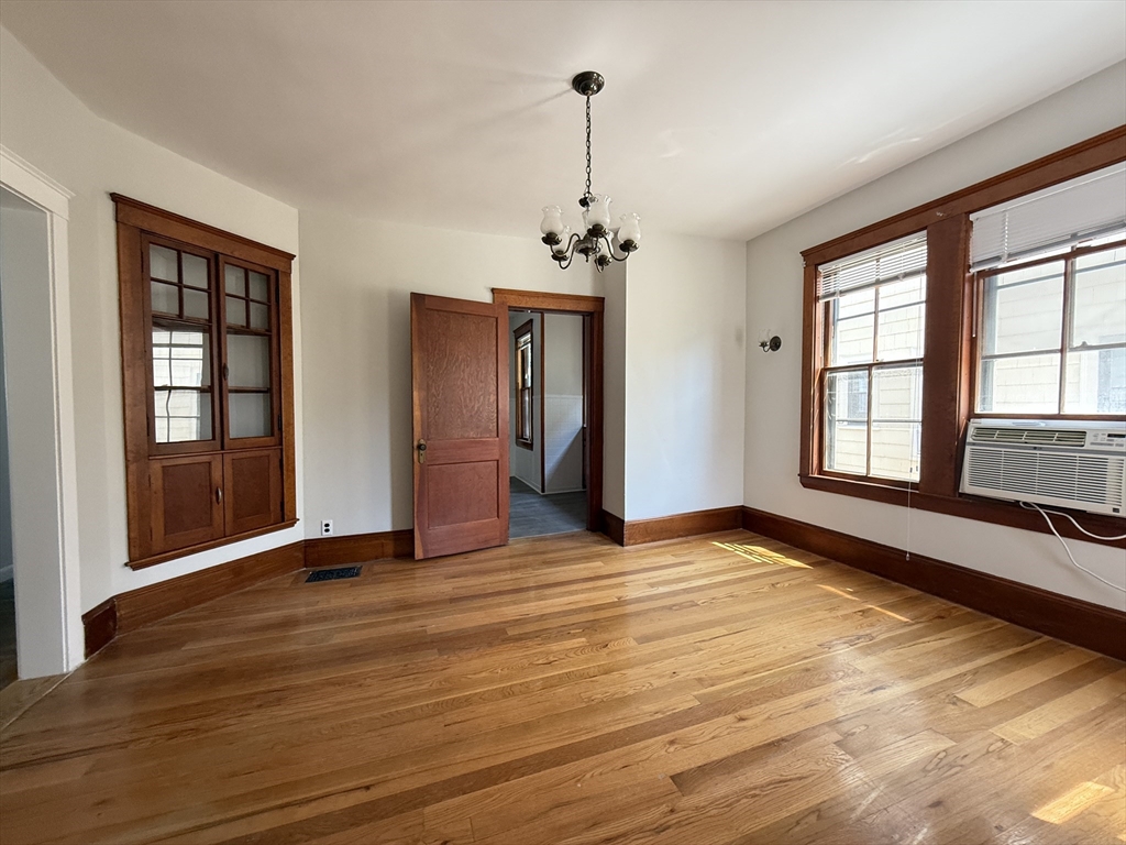 a view of an empty room with window and wooden floor