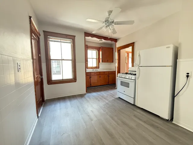 a view of a kitchen with refrigerator and wooden floor
