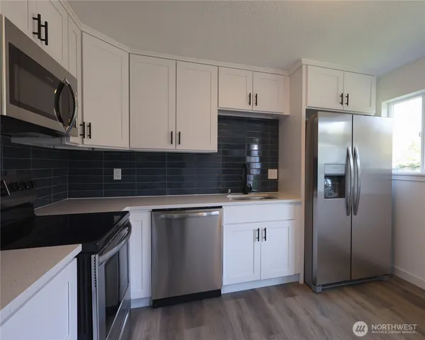 a kitchen with stainless steel appliances granite countertop a stove a refrigerator and a microwave